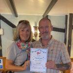 Photograph of Treasurer Josie Eddy handing a thank you certificate to Will Penno for fundraising money for the South West Liver Buddies